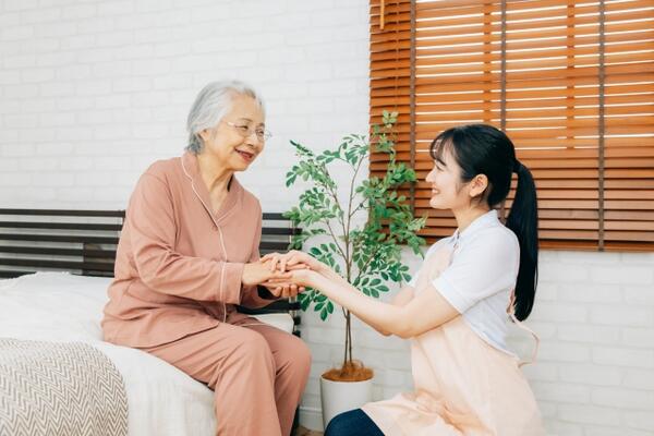 手を取り合う高齢者と介護士