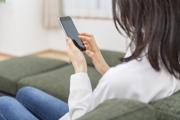 ソファーでスマホを操作する女性