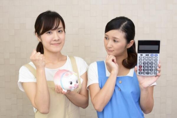 電卓と貯金箱を手にする女性介護士